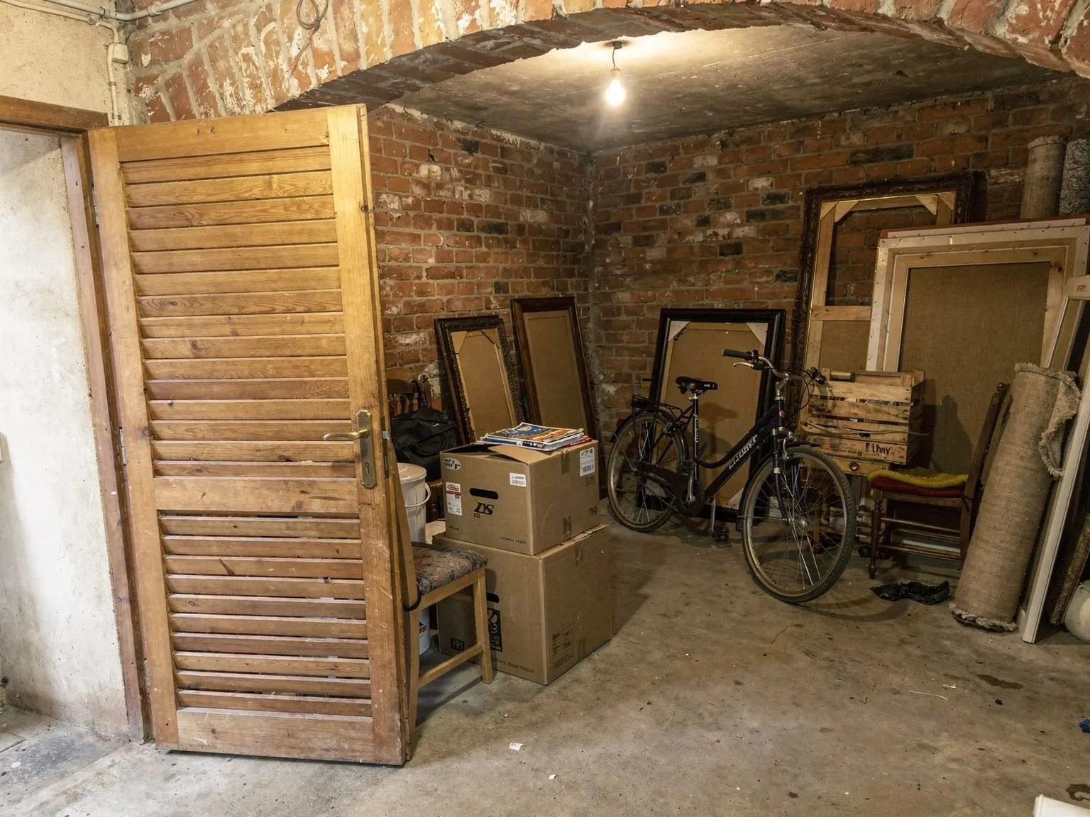 Cave en briques d’un immeuble de Lyon remplie de cartons et de vieux meubles