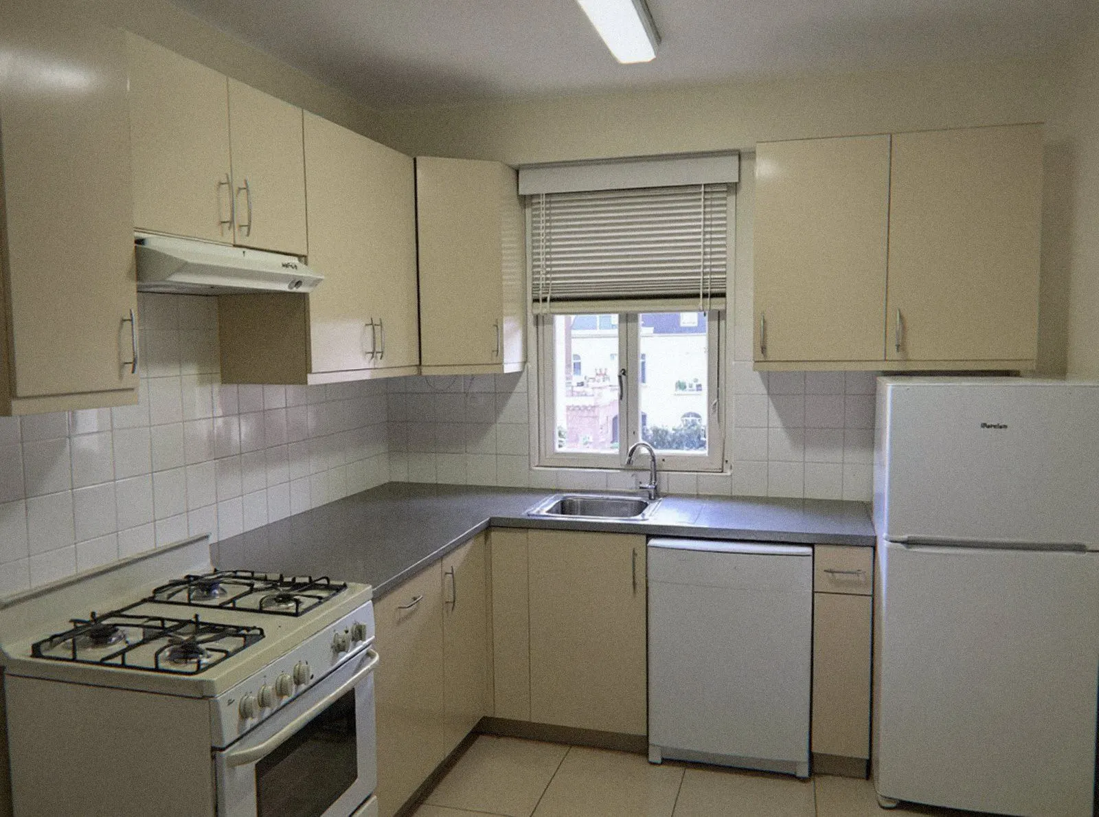 Cuisine d'appartement dégagée, réfrigérateur et meubles fixes seuls en place après le débarras à Lyon