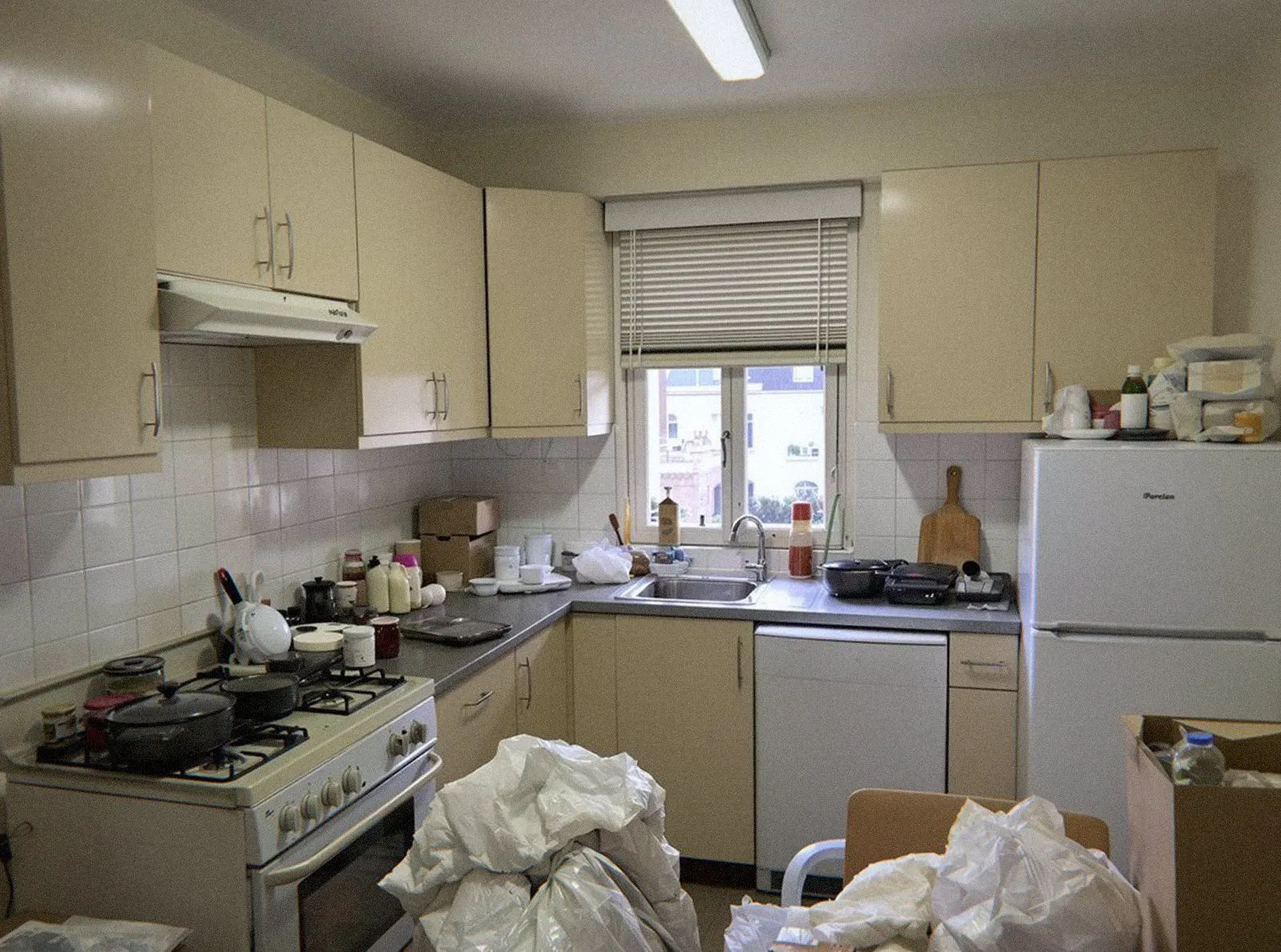 Cuisine d'appartement encombrée de sacs, de cartons et d'un meuble d'appoint avant le débarras