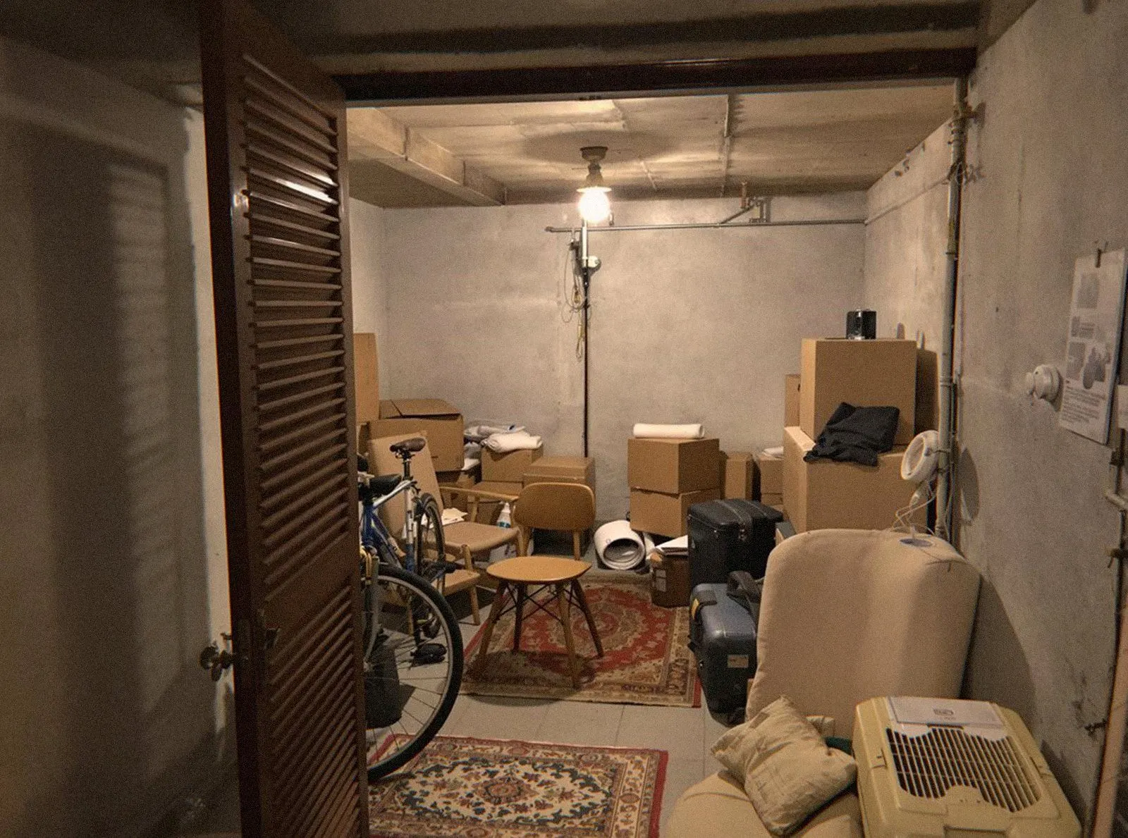 Cave aux murs de pierre remplie de cartons, de cadres et de vieux meubles avant un débarras de cave à Lyon