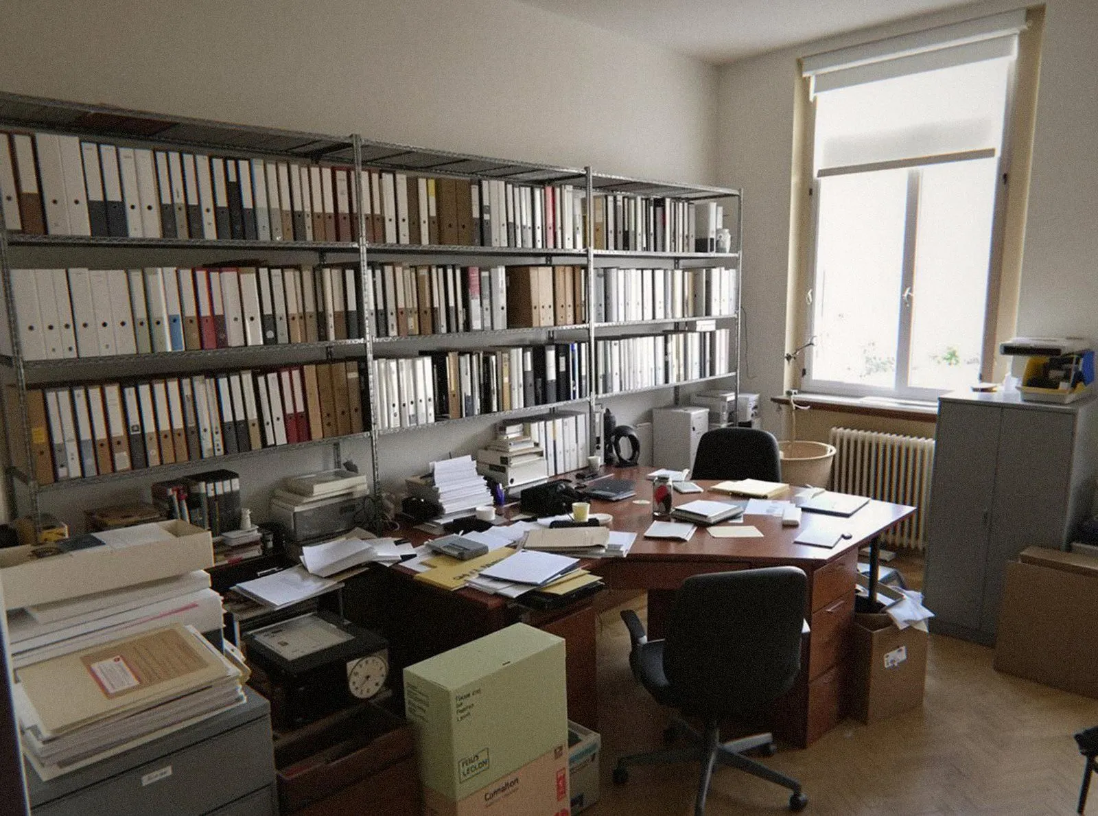 Bureau professionnel envahi de dossiers, de classeurs et de cartons d'archives avant un débarras à Lyon
